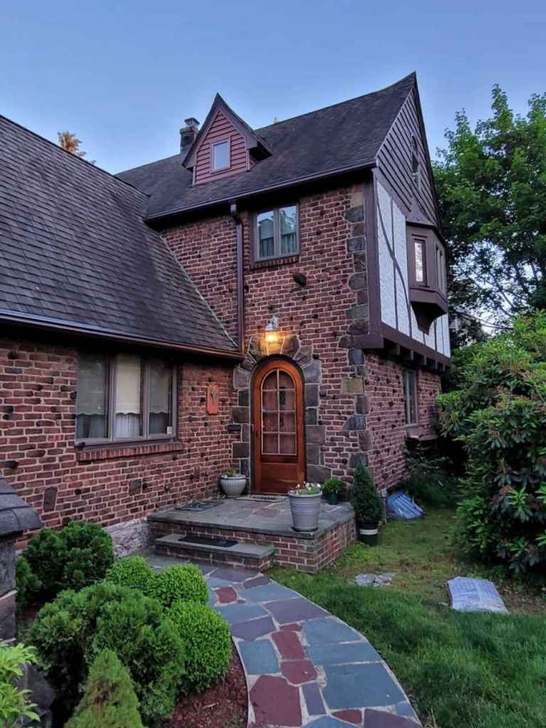 A Tudor style house with brown gutters that seamlessly blend in with the house architecture.