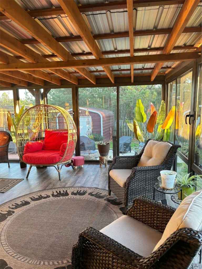 A spacious sunroom full of natural light with windows in full view of the yard.