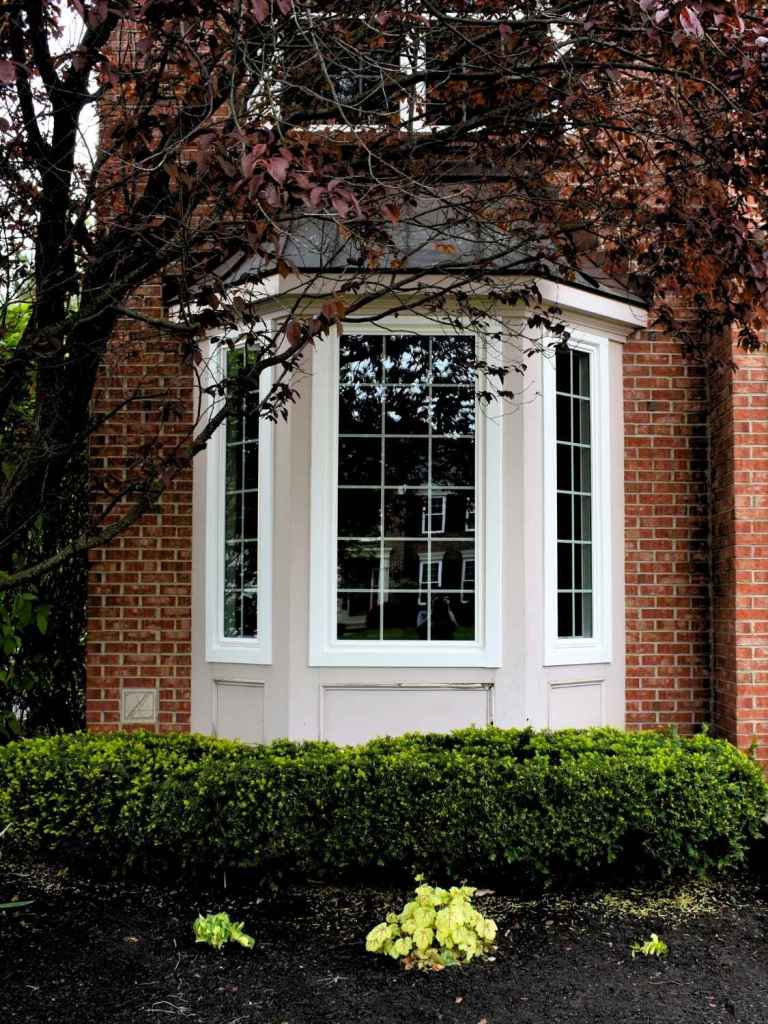 A close up of a bay window on the side of a brick house.